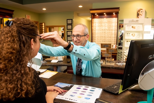 Photo of a person putting glasses on another person.